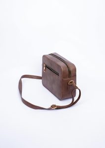 Stylish brown leather crossbody bag displayed against a white background in a studio shoot.